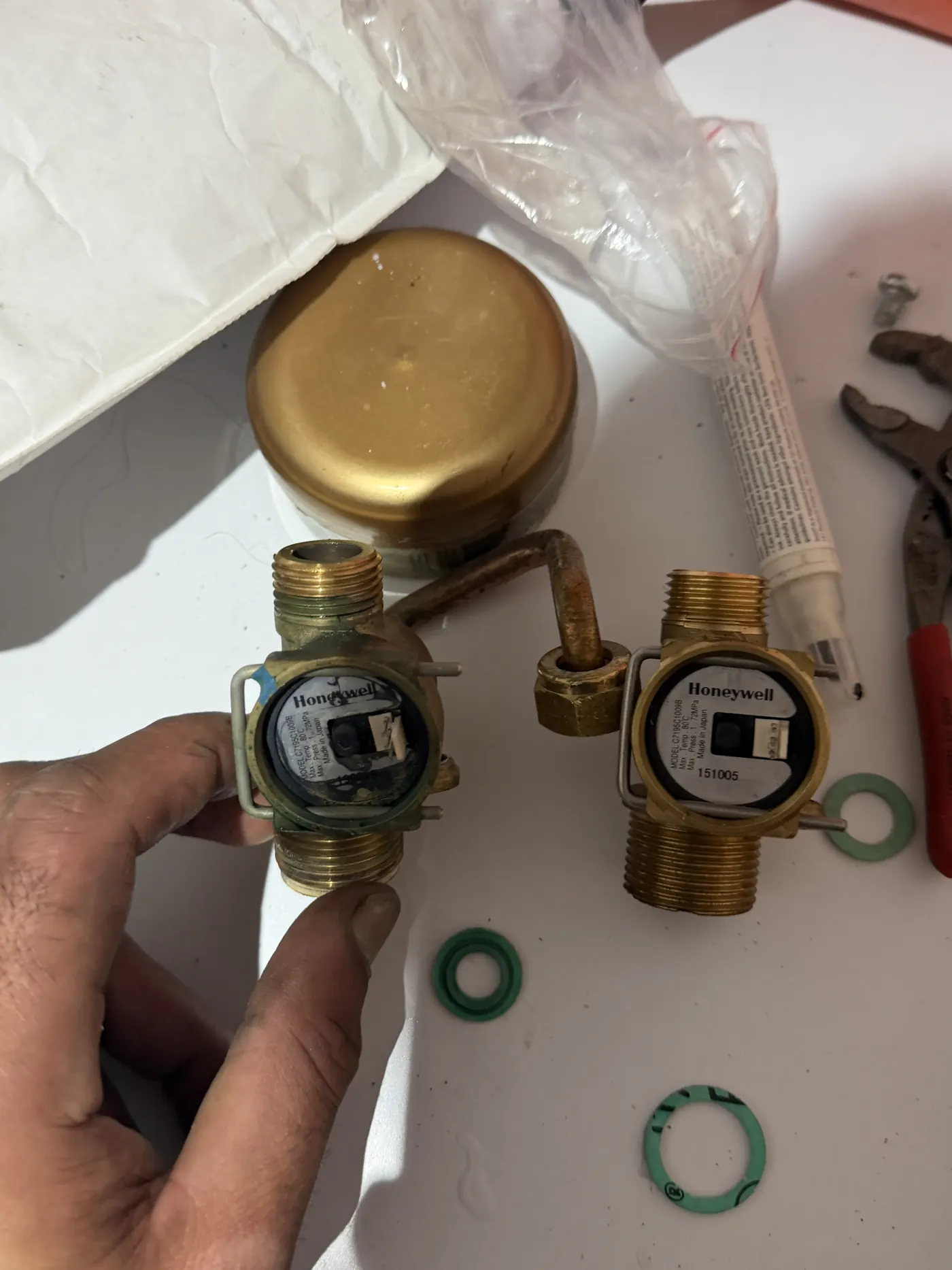 Old and new Honeywell flow switches side by side with new fibre washers before fitting