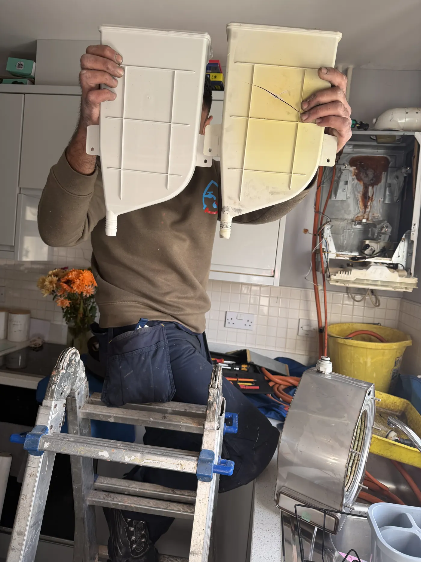 The cracked, discoloured old flue collector held next to the new replacement