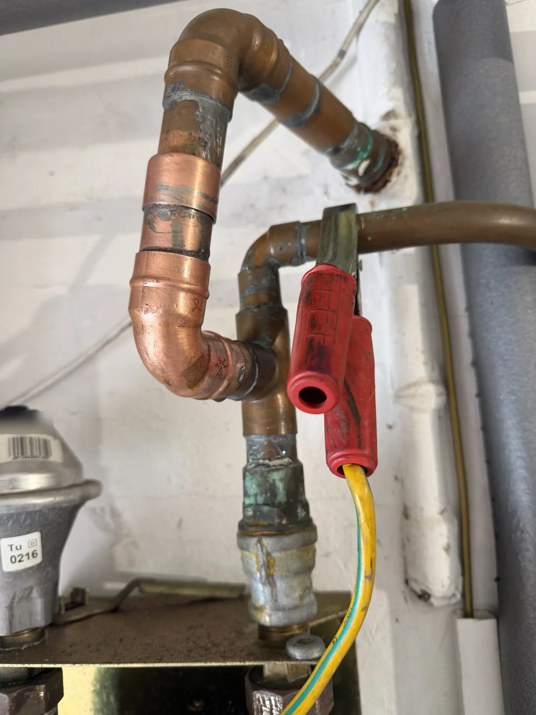 Gas pipework at the meter outlet in an Edgbaston home after the repair, with a red temporary bonding clamp and yellow and green cable fitted across the pipe