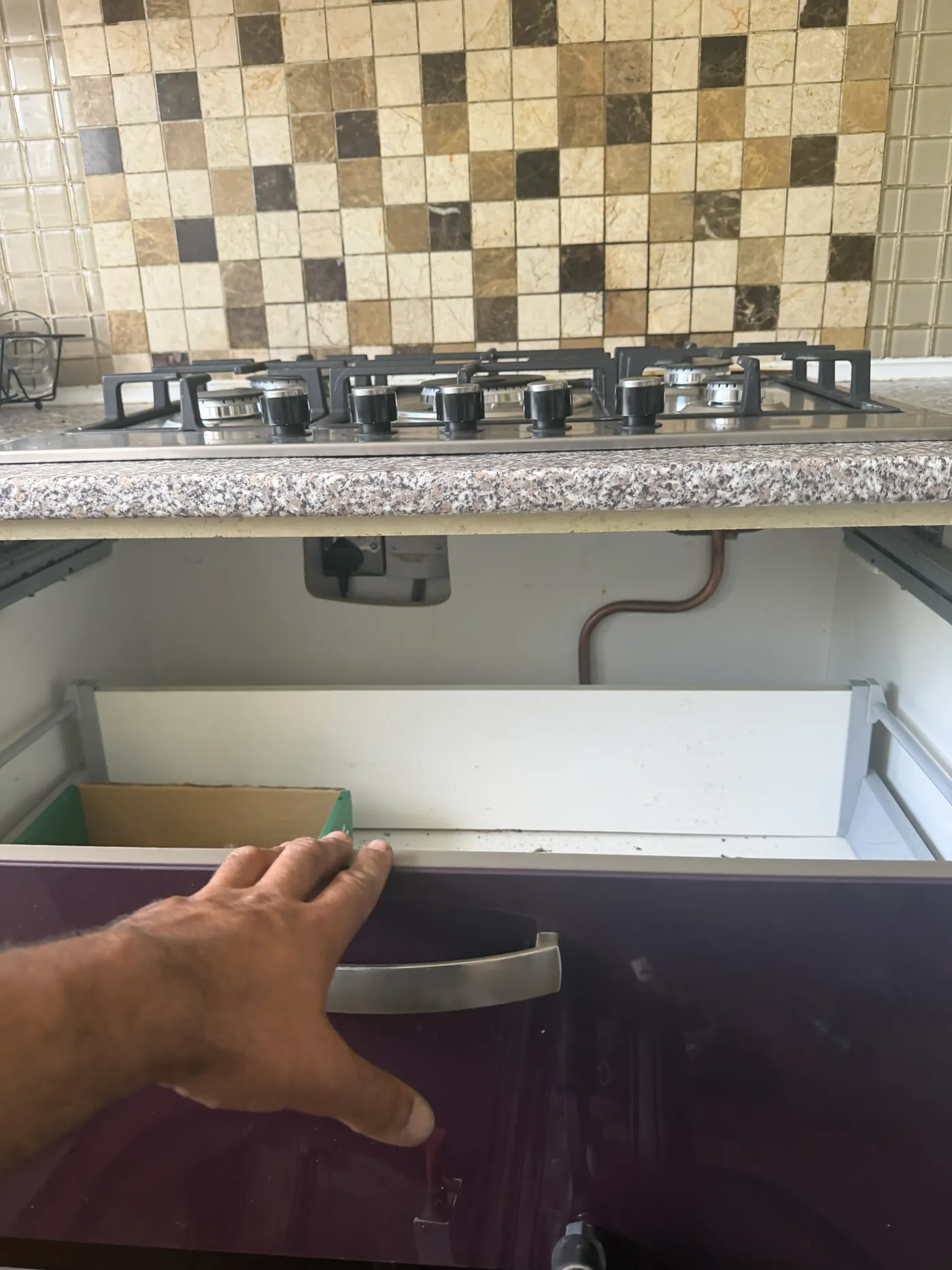 Copper gas connection to the new hob under the worktop, viewed through the open cupboard