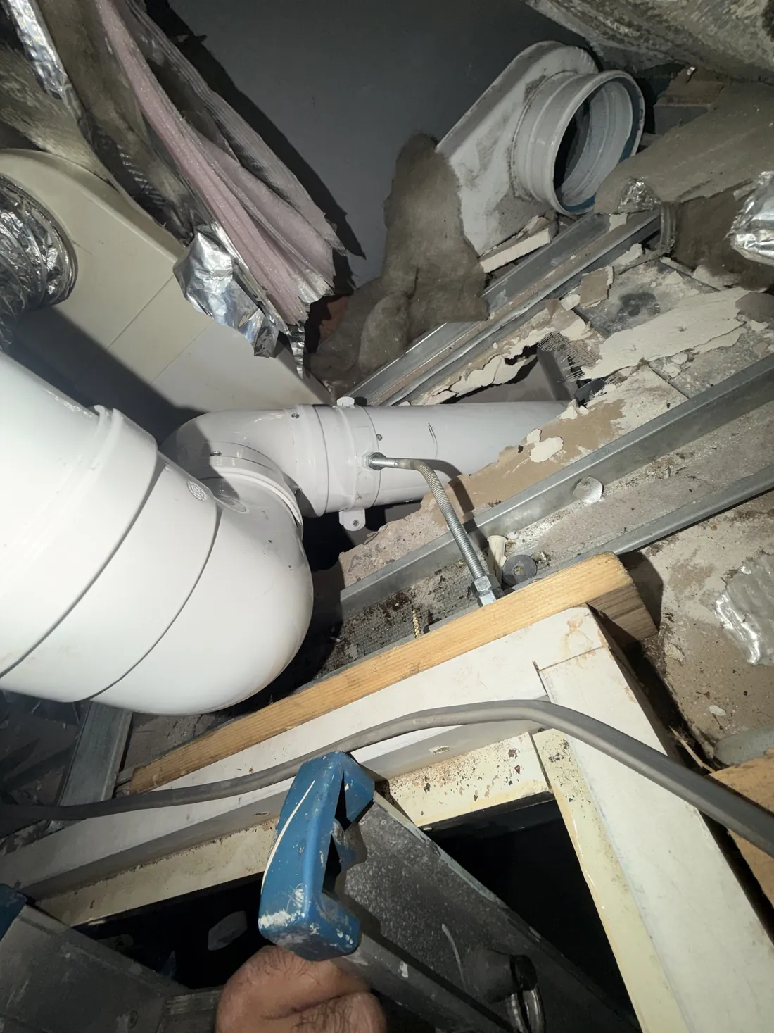 New white boiler flue in the ceiling void above the cupboard, held by a bracket on a threaded rod