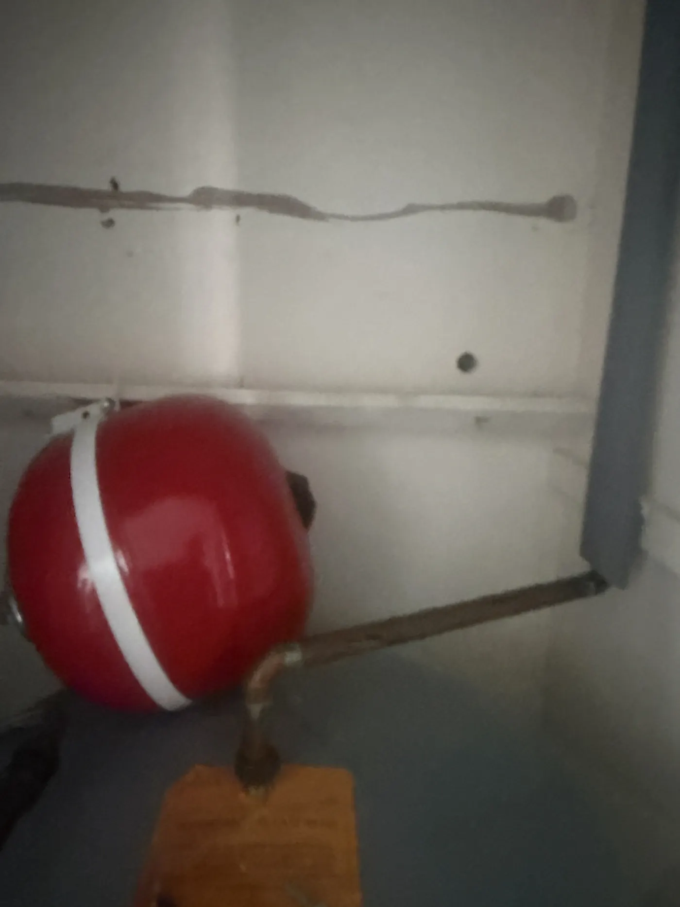 Red expansion vessel hanging off its copper pipe after the nailed backboard came away from a plasterboard wall