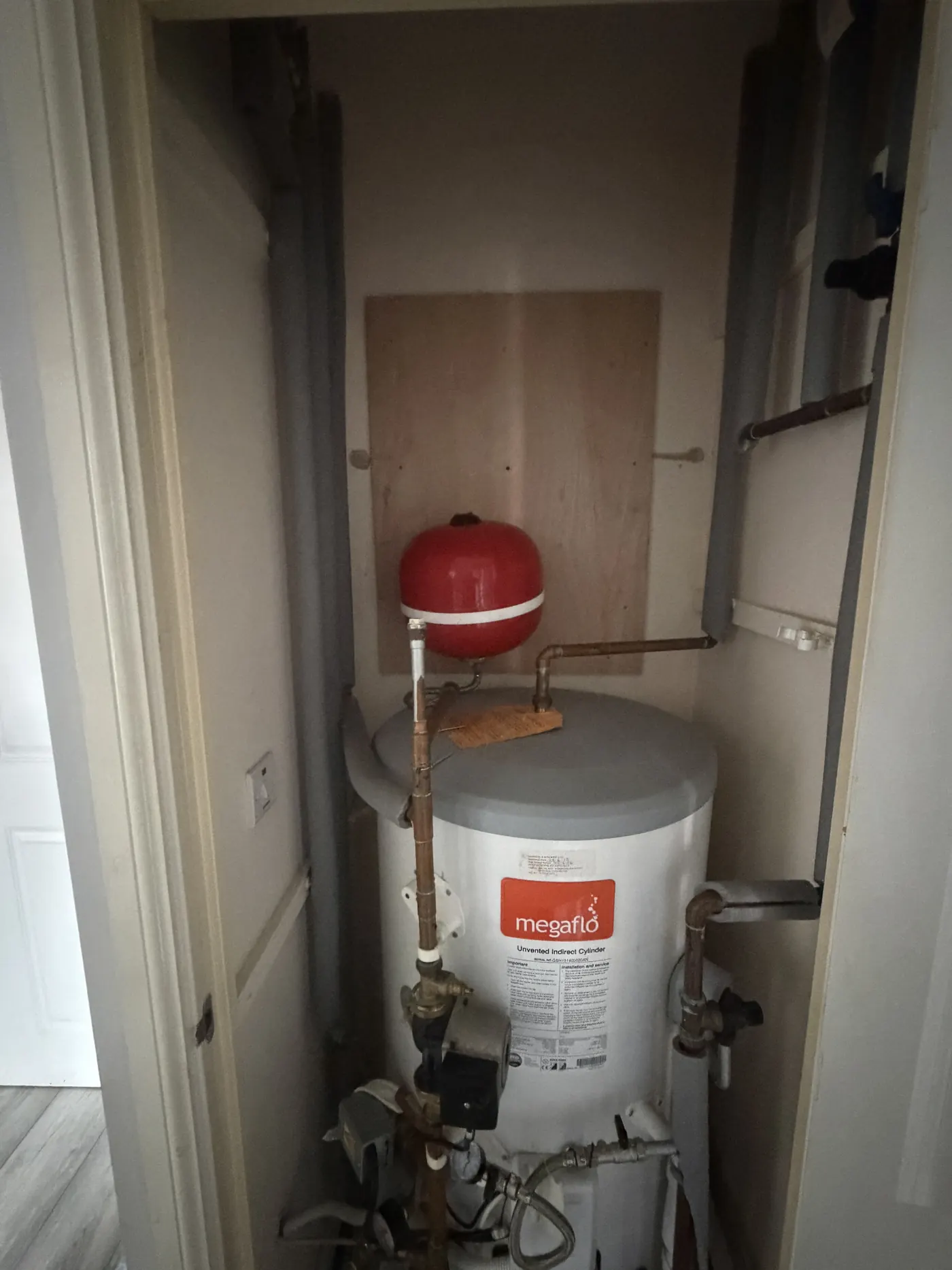 Expansion vessel remounted on a new plywood backboard beside a Megaflo unvented cylinder in Hockley