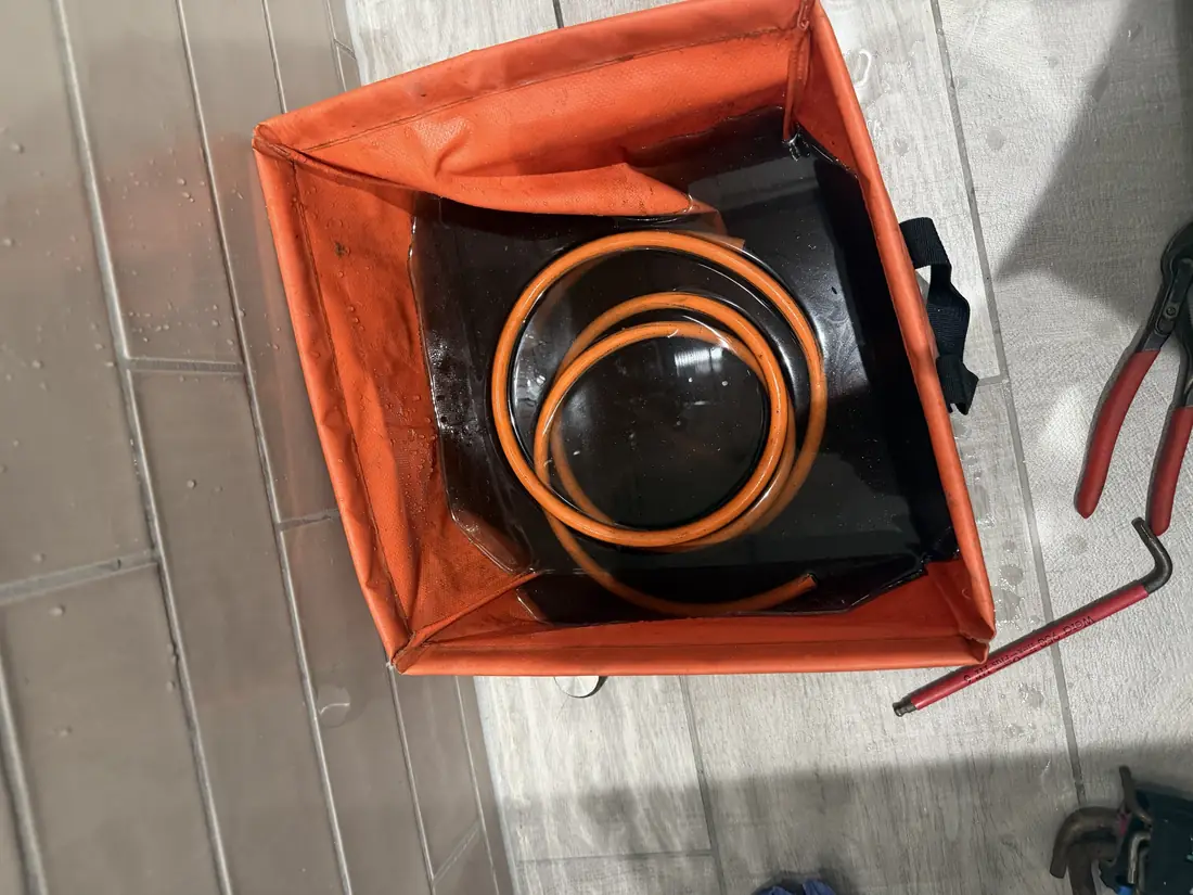 Dark brown water drained from the heat interface unit system into an orange drain tray on the apartment floor