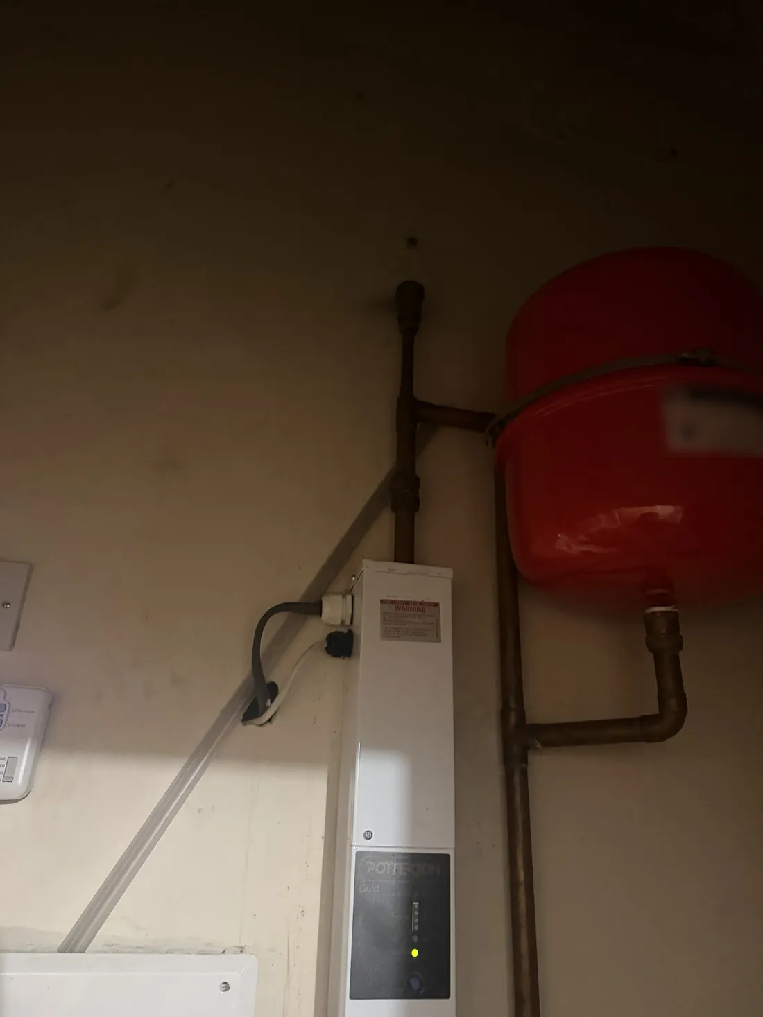 Potterton Gold electric boiler on a cupboard wall beside its red expansion vessel and copper pipework