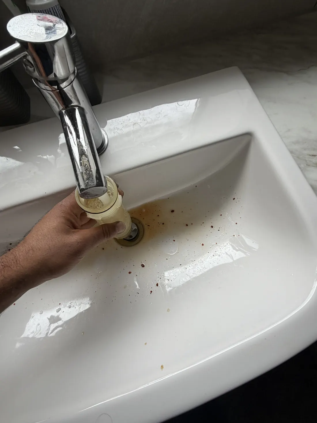 Condensate trap from the Vaillant boiler being rinsed clean under a basin tap during the service
