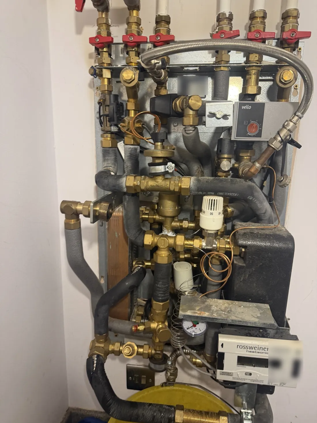 Inside a Meibes heat interface unit with the expansion vessel moved aside, showing the plate heat exchanger, pump, valves and heat meter
