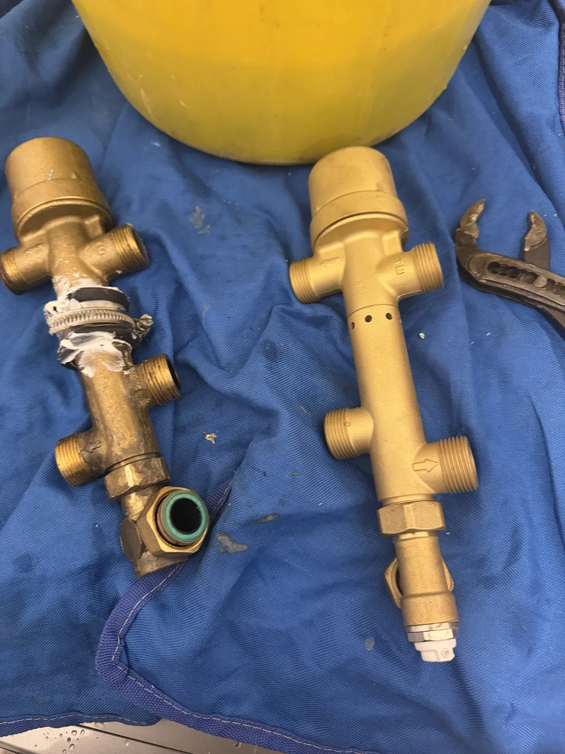 Old PM valve with sealant and a hose clip around its joint, beside a clean new replacement valve