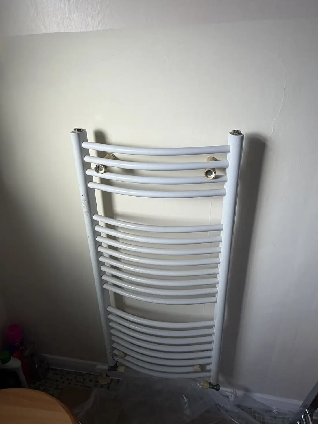 The old white curved towel radiator on the bathroom wall in Rowley Regis before replacement