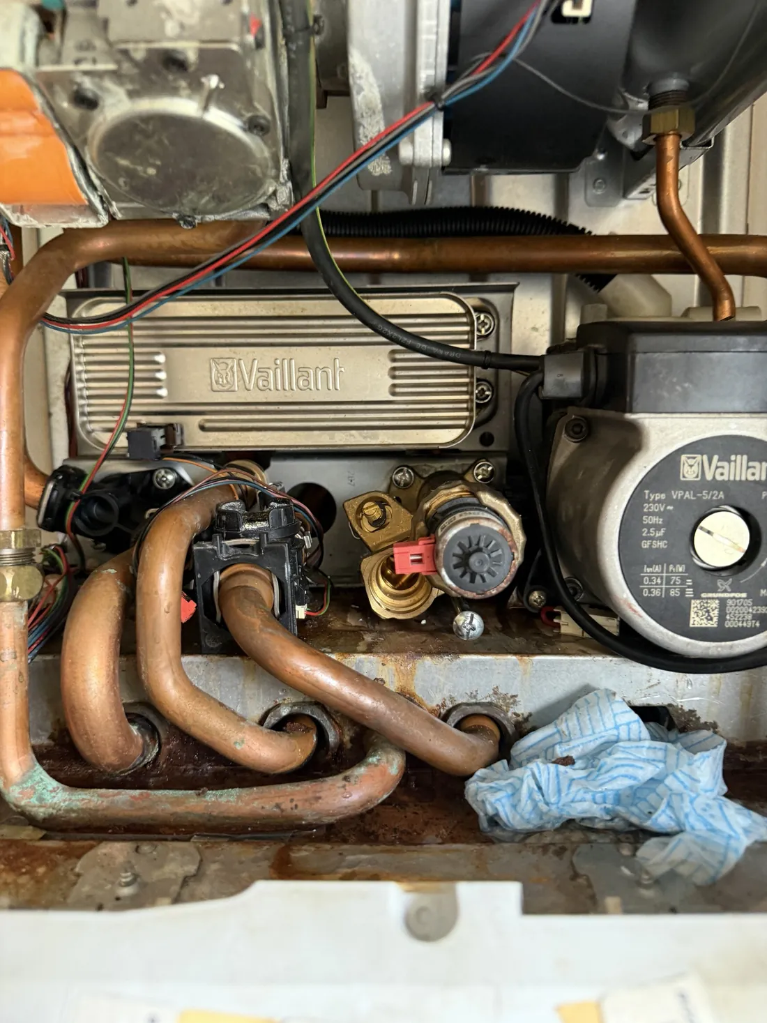 Hydraulic components at the bottom of a Vaillant ecoTEC pro 28 with a cloth laid down during the service