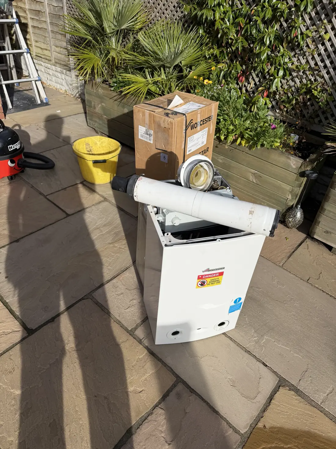 The removed Worcester Greenstar Ri and its flue on a patio next to the boxed new Worcester boiler