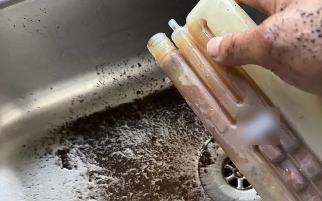 The blocked condensate trap out of a Potterton Assure, with the sludge and debris that blocked it in the sink
