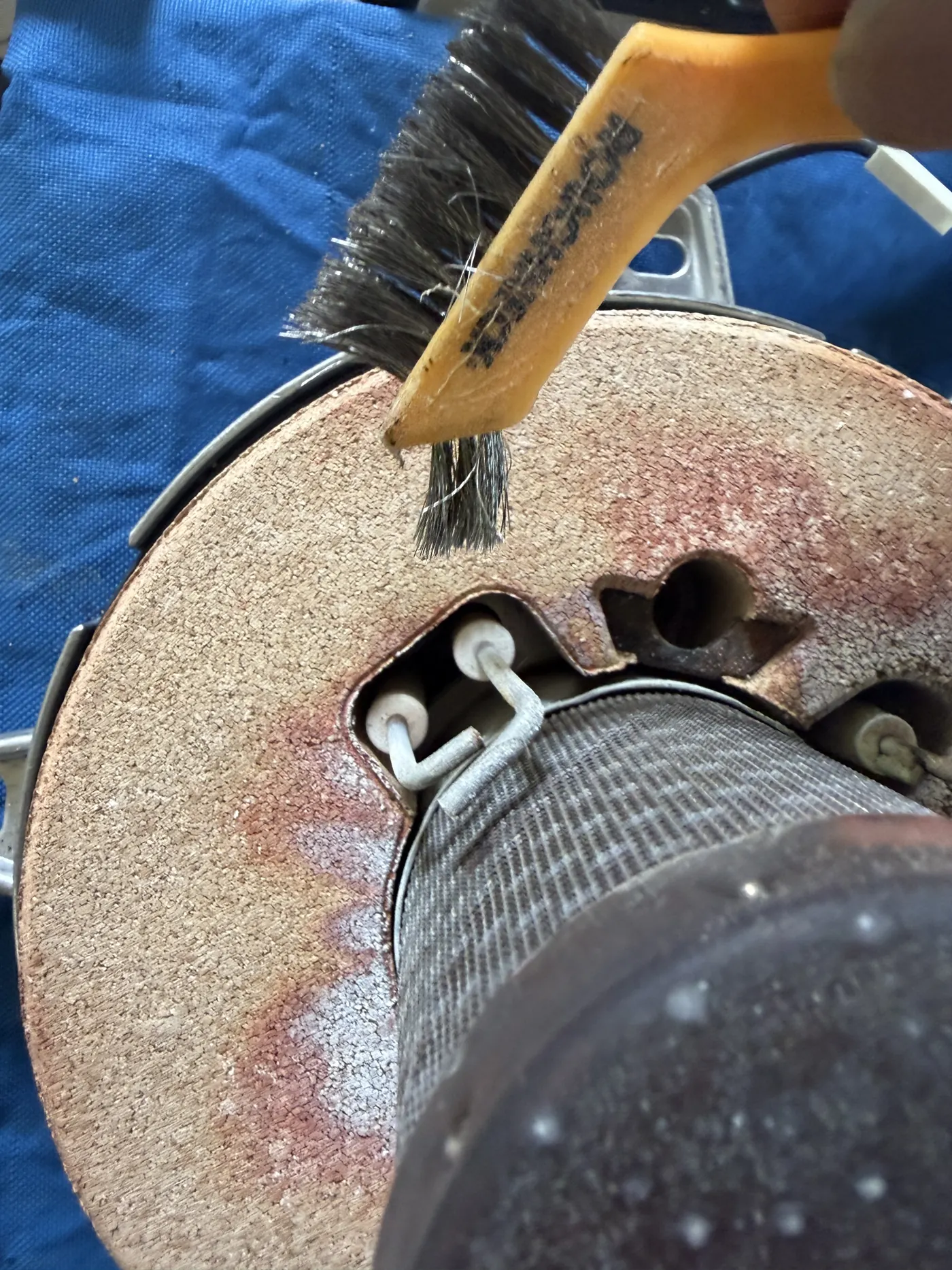 Engineer wire-brushing the burner door insulation and electrodes on the Viessmann burner assembly