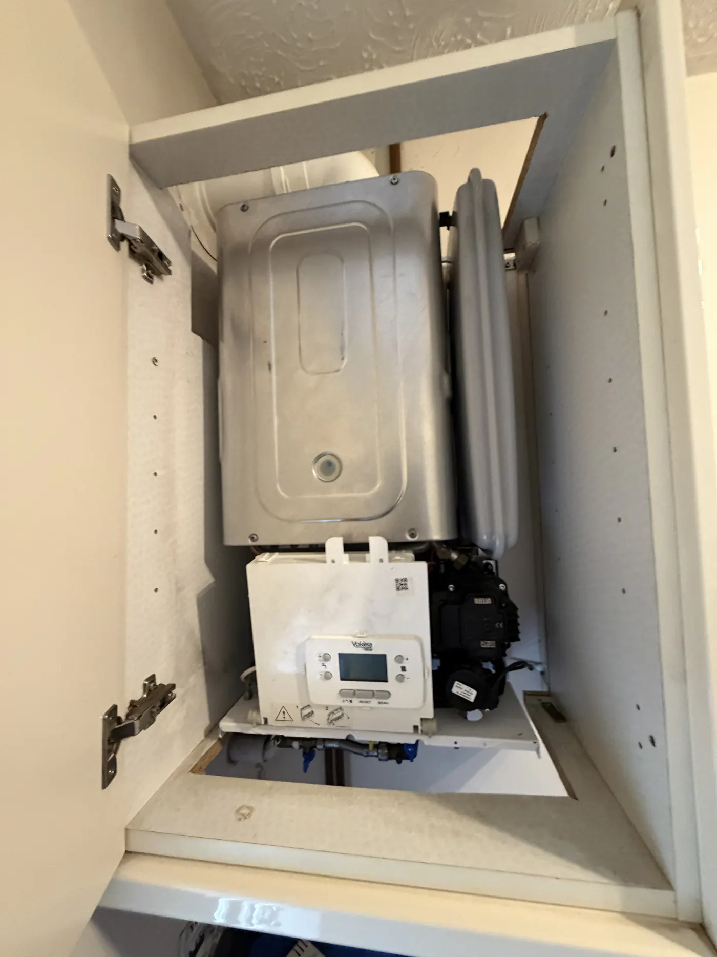 Vokera boiler installed inside a kitchen wall cupboard with the cupboard door open