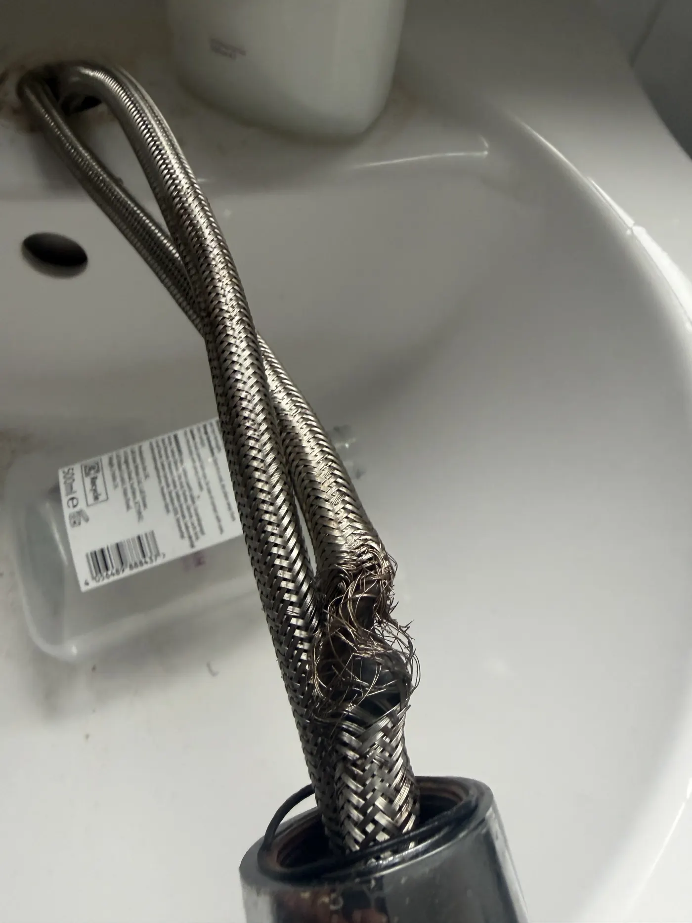 Braided flexi hose removed from the tap, with the stainless braid frayed open where it failed