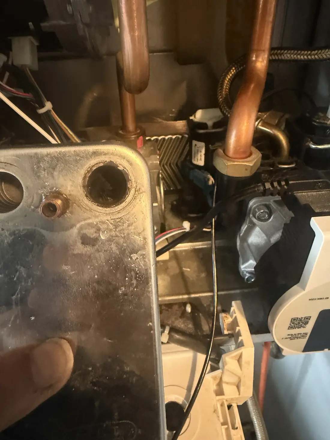 The stainless steel plate heat exchanger removed from the Biasi Advance, held beside the open boiler