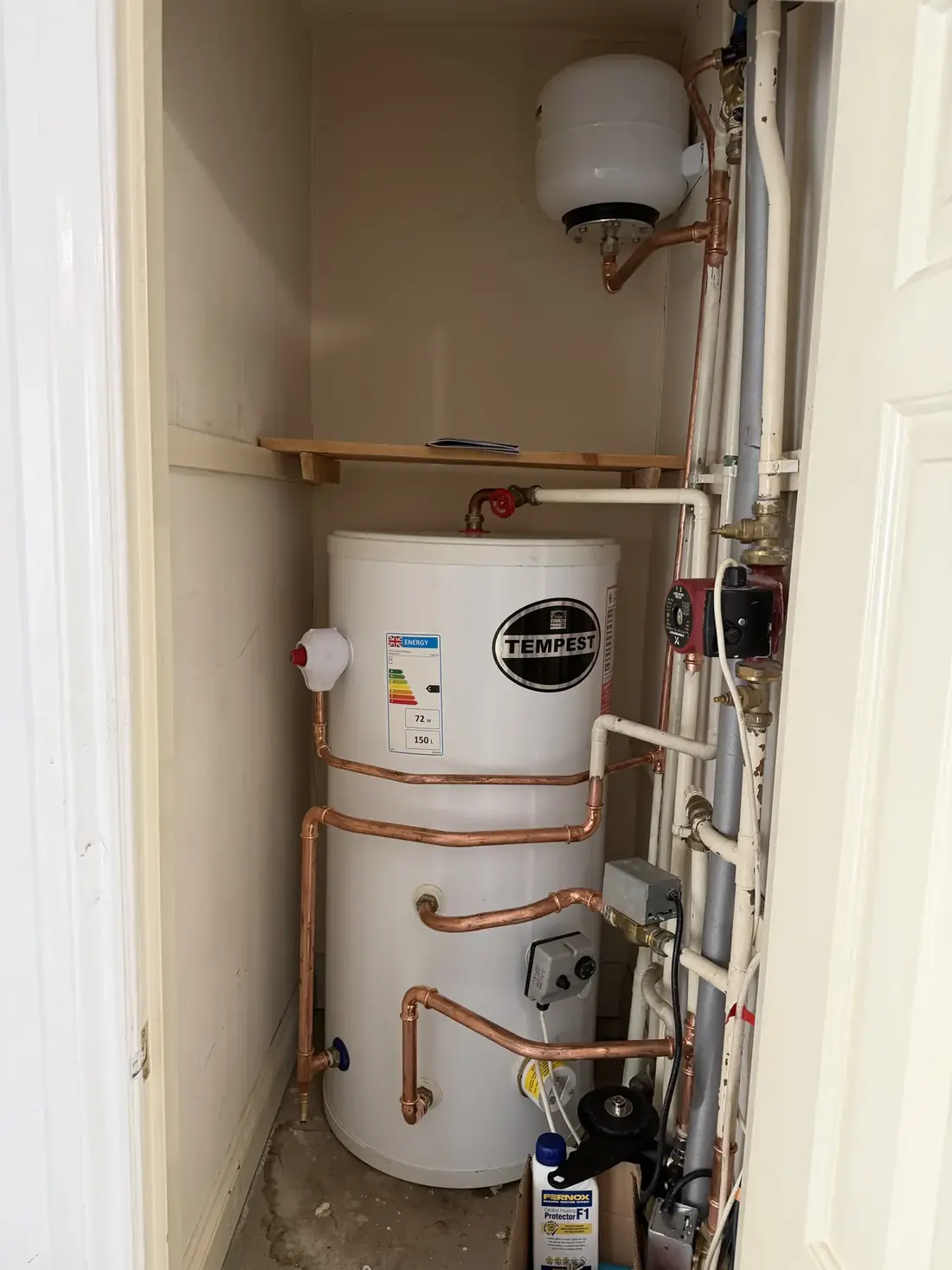 The new 150-litre stainless steel unvented cylinder installed in the cupboard with new copper pipework and expansion vessel