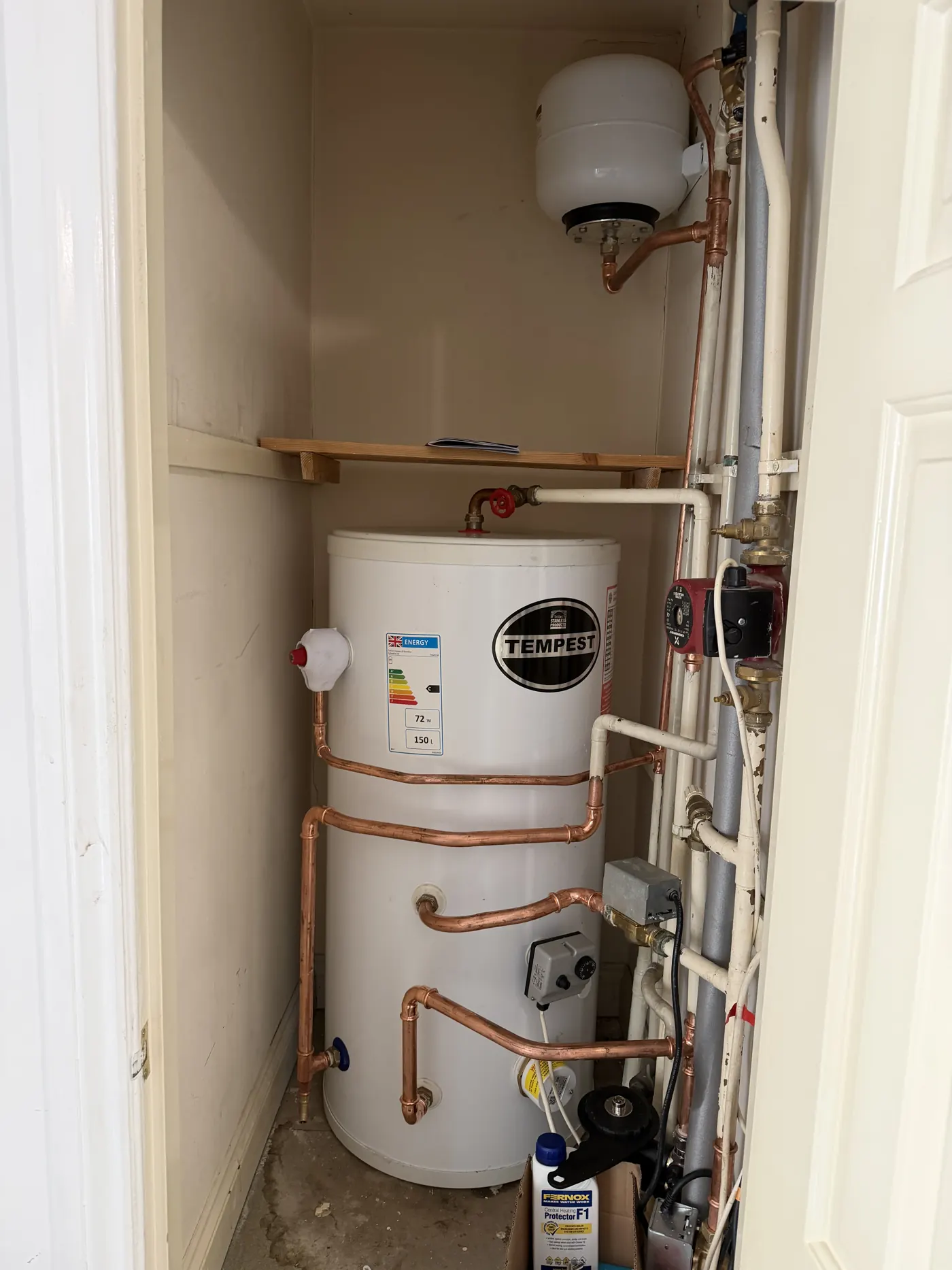 The new 150-litre stainless steel unvented cylinder installed in the cupboard with new copper pipework and expansion vessel